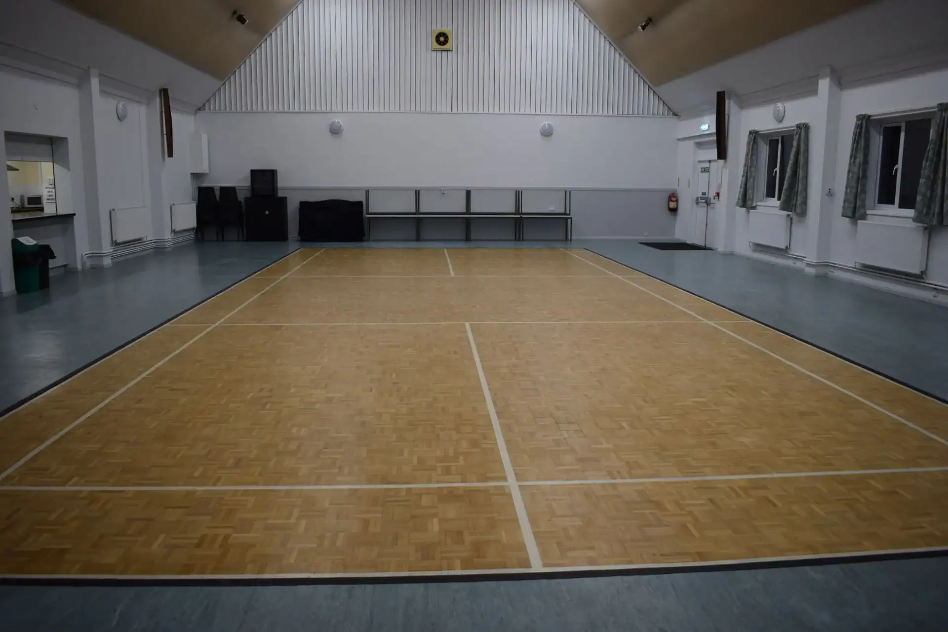 Indoor sports hall with wooden flooring and spacious area for events and activities.