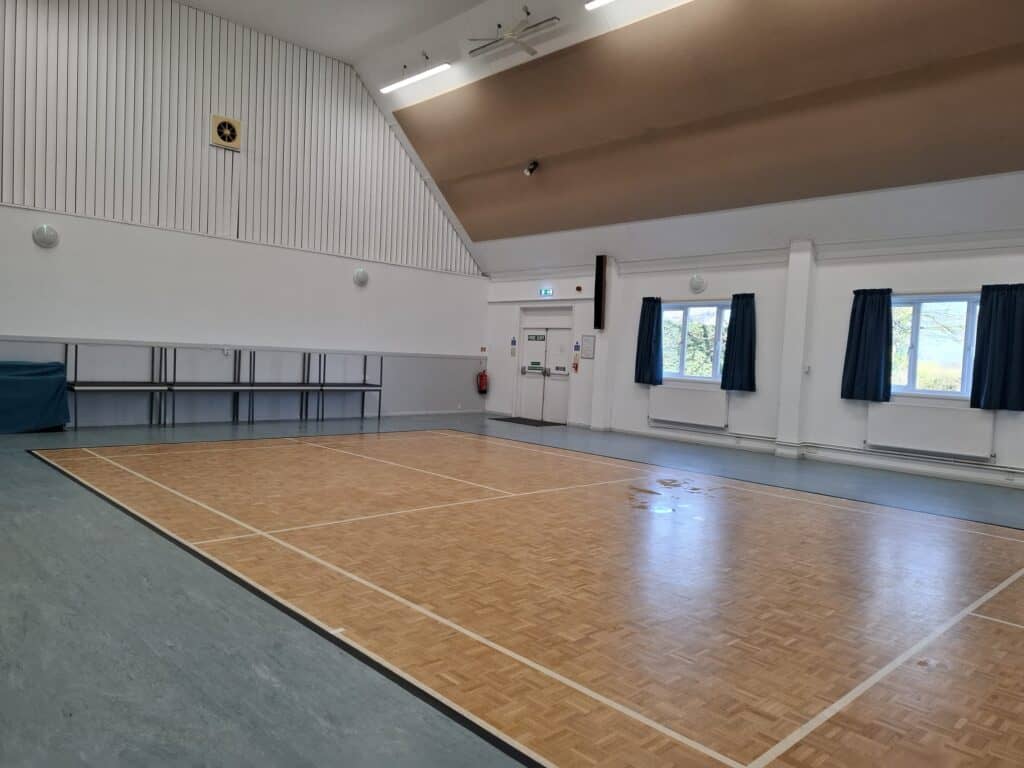 Indoor sports hall with wooden flooring, ideal for community events, sports, and recreational activi.