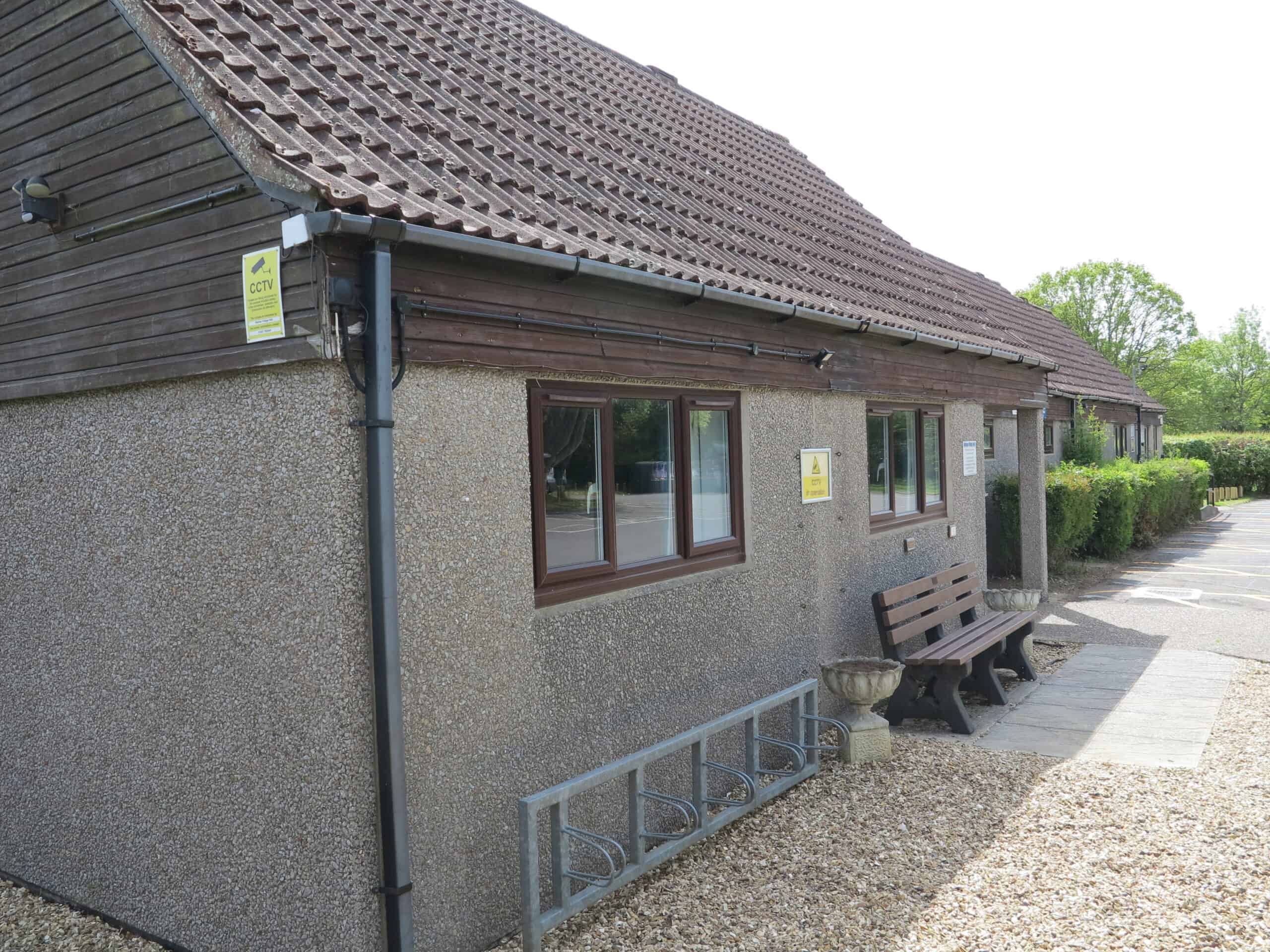 Community hall building with benches and greenery.