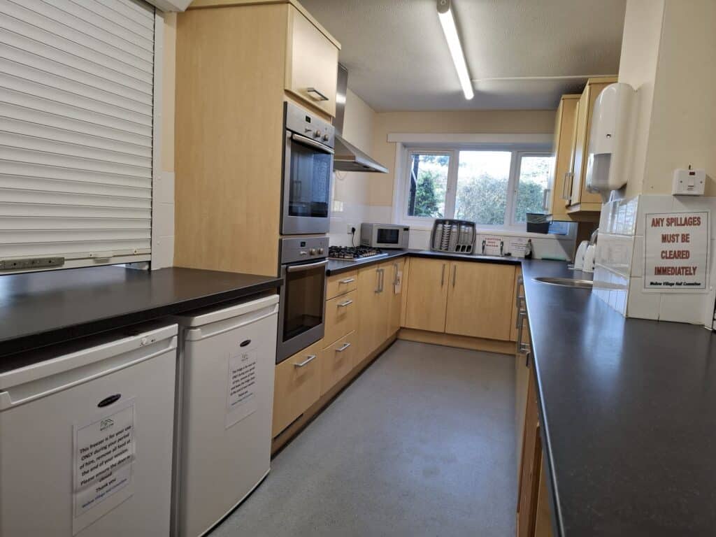 Kitchen with modern appliances and large window providing natural light at Wellow Village Hall.